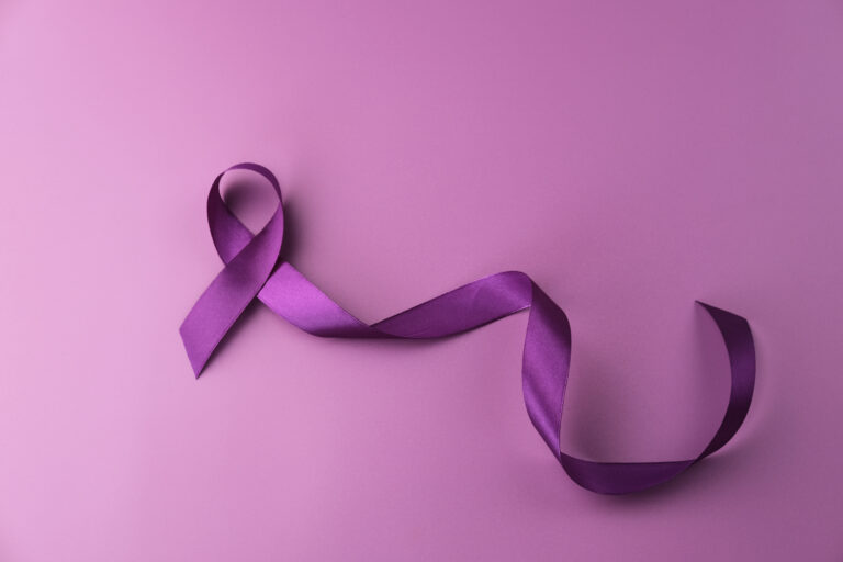A purple ribbon is artfully arranged on a matching purple background, symbolizing awareness and support for various causes such as domestic violence prevention, lupus, epilepsy, and Alzheimer's disease.
