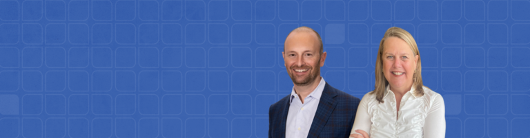 A smiling man in a suit and a smiling woman in a white blouse stand against a blue patterned background. The woman, who has her arms crossed, exudes confidence and warmth.