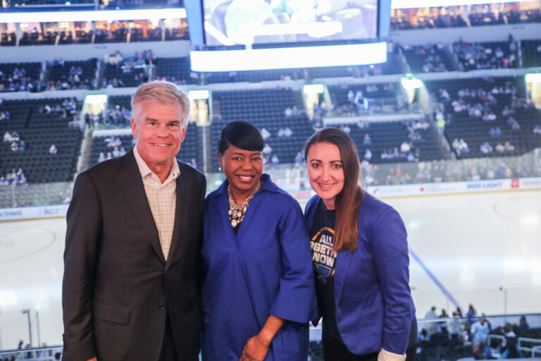 United Way president and CEO, Michelle Tucker, stands with campaign vice-chair in front of the ice at the St. Louis Blues game