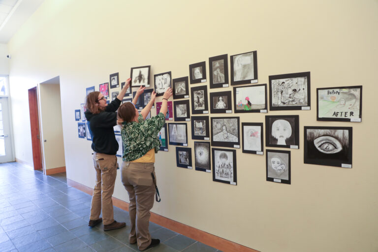 Hanging pictures from 100 Neediest Cases in the Missouri History Museum