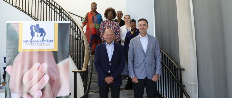 United Way campaign chairs stand on stairs at a UW partner agency.